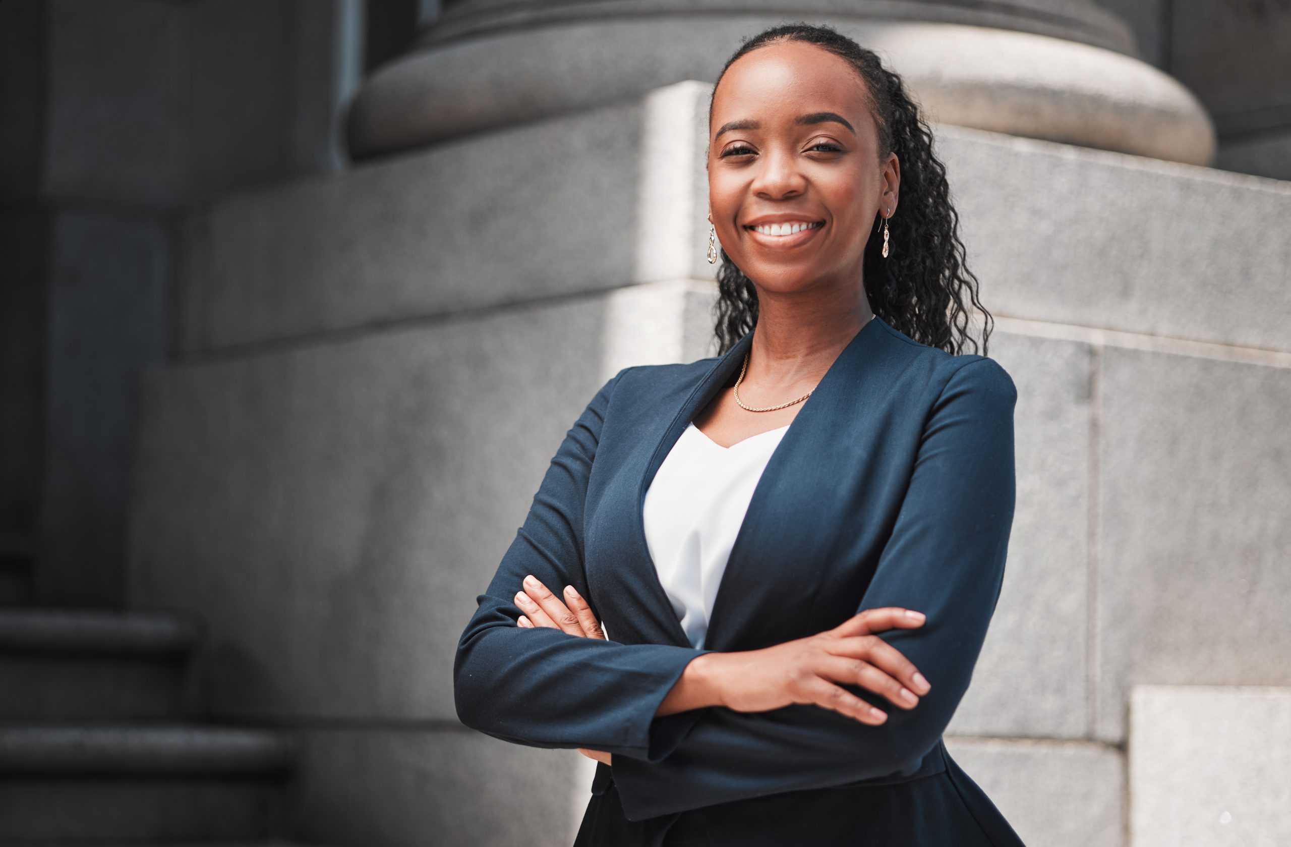 Arms crossed, lawyer or portrait of happy black woman with smile or confidence working in a law firm. Confidence, empowerment or proud African attorney with leadership or vision for legal agency.